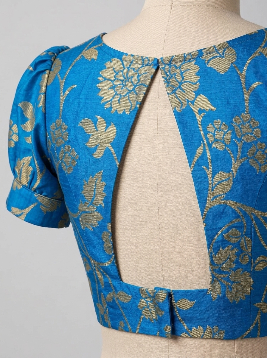 Close-up back view showing the open cutout back and hook closure of the blue brocade blouse