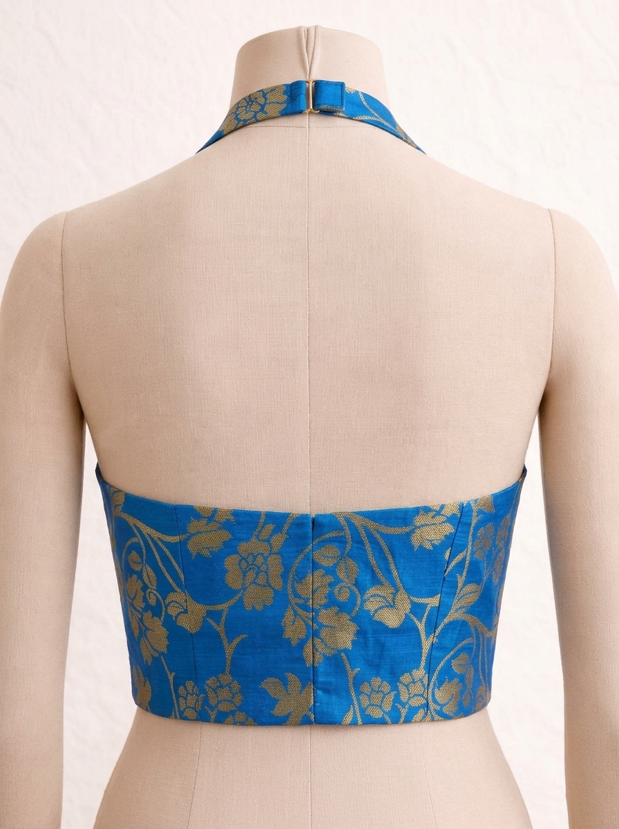 Back view of royal blue saree blouse on mannequin showing open back design and halter neck metal clasp closure.