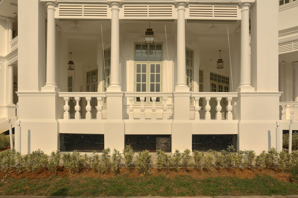Restored colonnaded balcony and timber louvers of Seri Negara heritage mansion, showing white architectural facade detailing.
