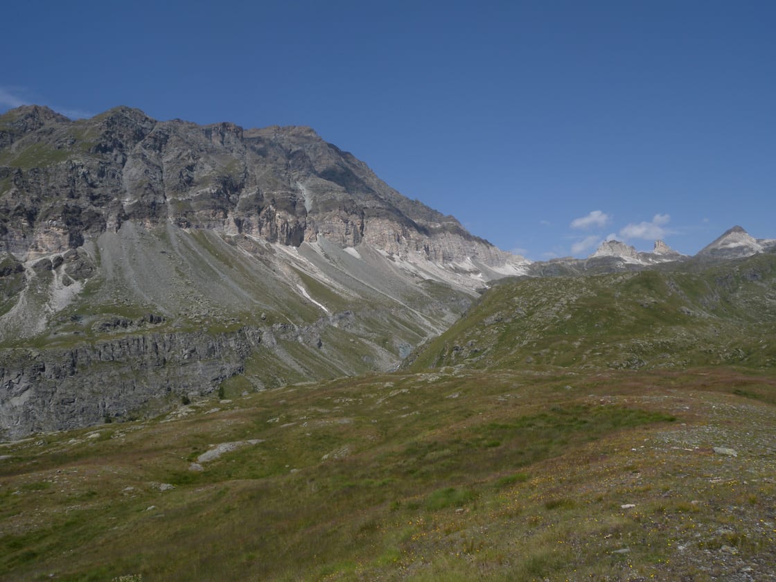 11. Il gran versante destro del vallone mostra, dal basso verso l'alto, le metabasiti (antichi magmi oceanici), la fascia bianca (antiche lagune ante-oceaniche) e infine i metasedimenti (antichi fanghi di alto mare).