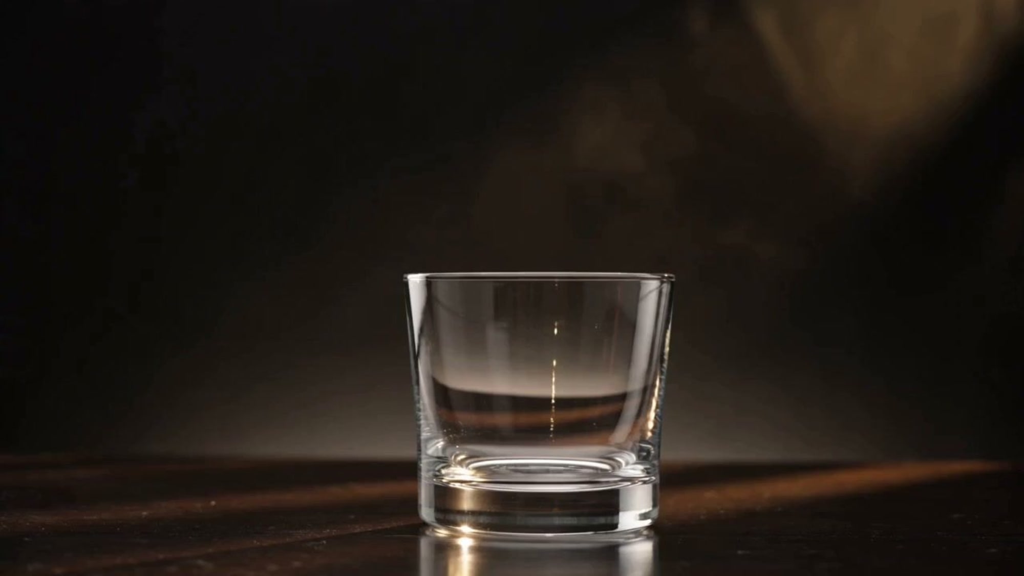 An empty whisky glass waiting on a dark bar