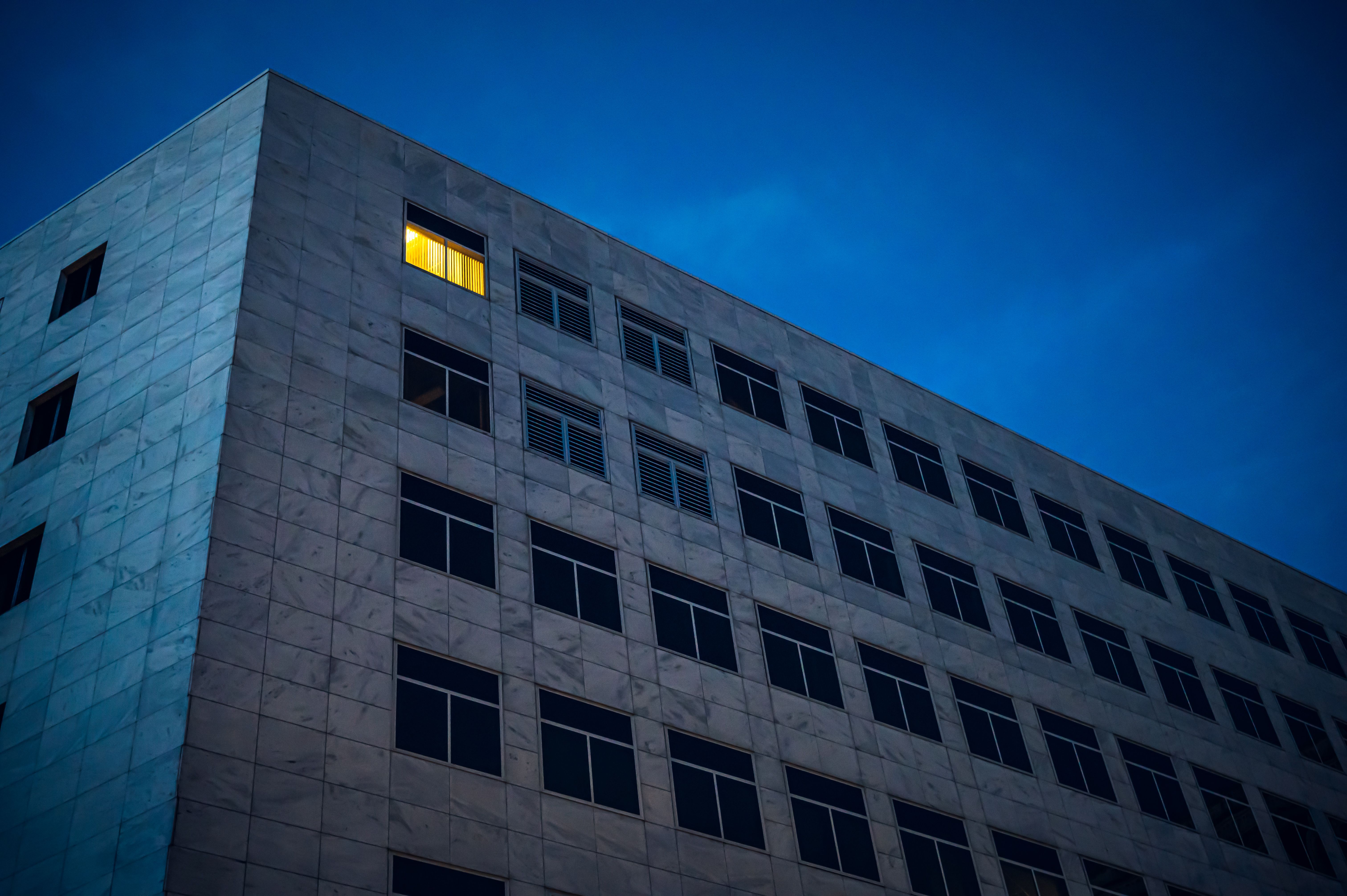 A lone building at night with a single lit window against a dark sky