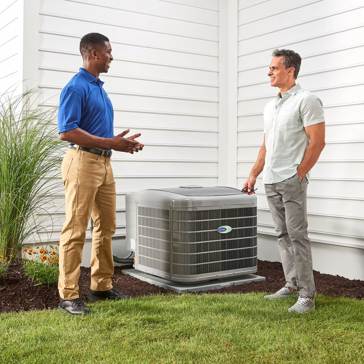 Carrier technician with homeowner outdoors in front of carrier air conditioner