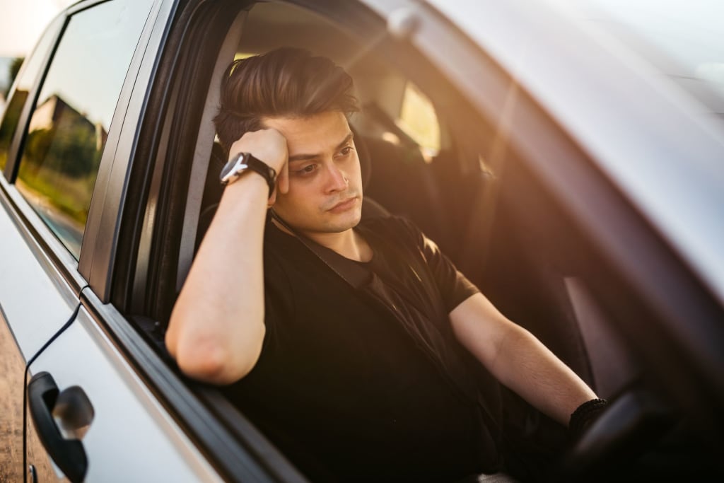 A young driver sitting in a car with the window down