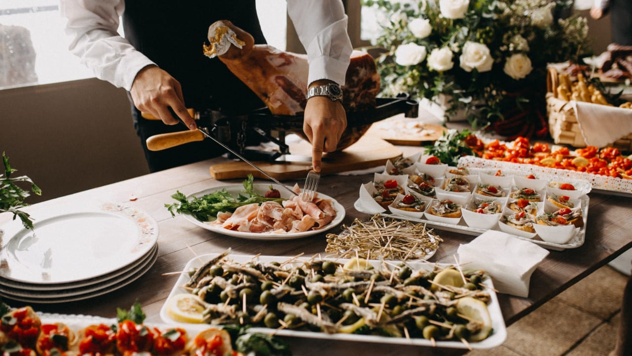 event server serving appetizers at a food station for an event. 