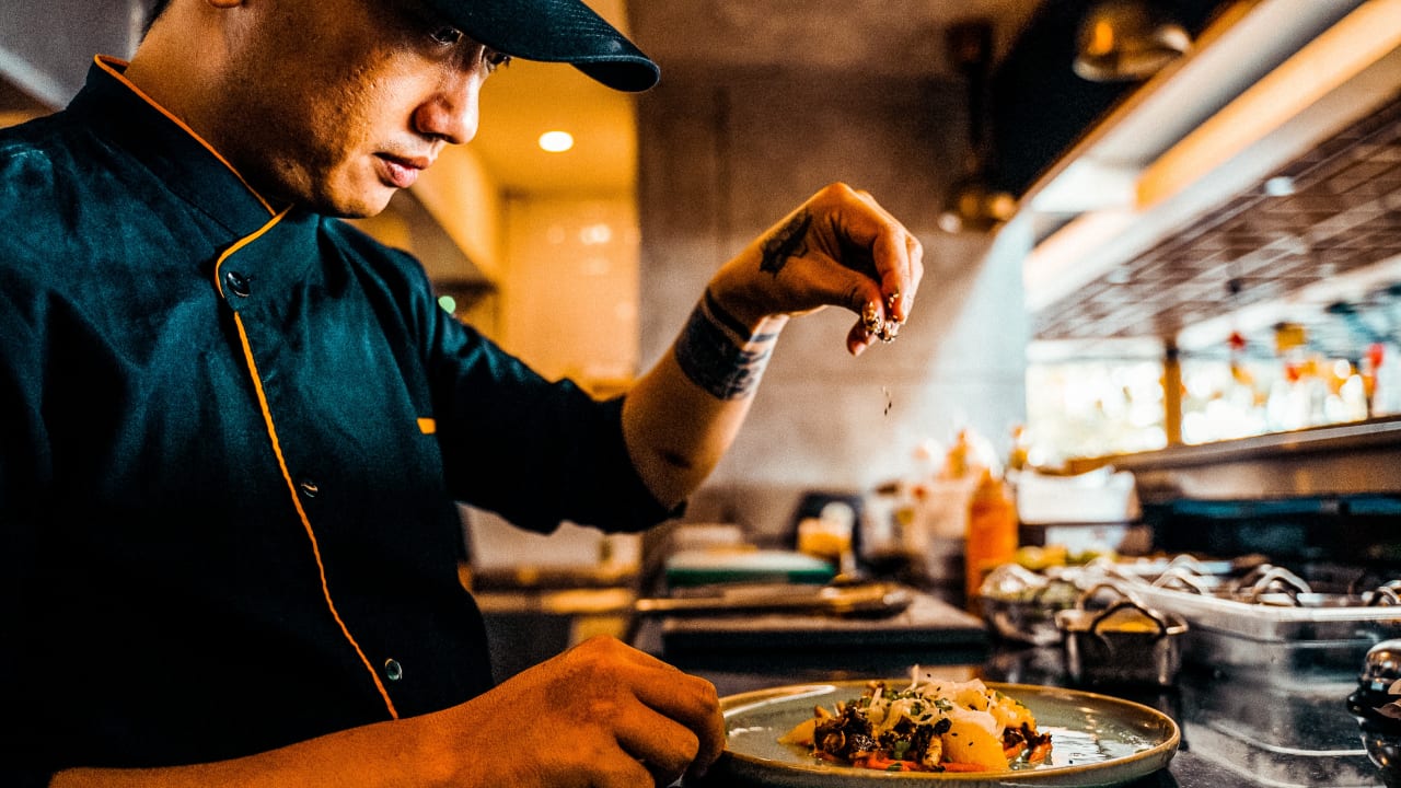 Gigpro Line cook seasoning a dish. 