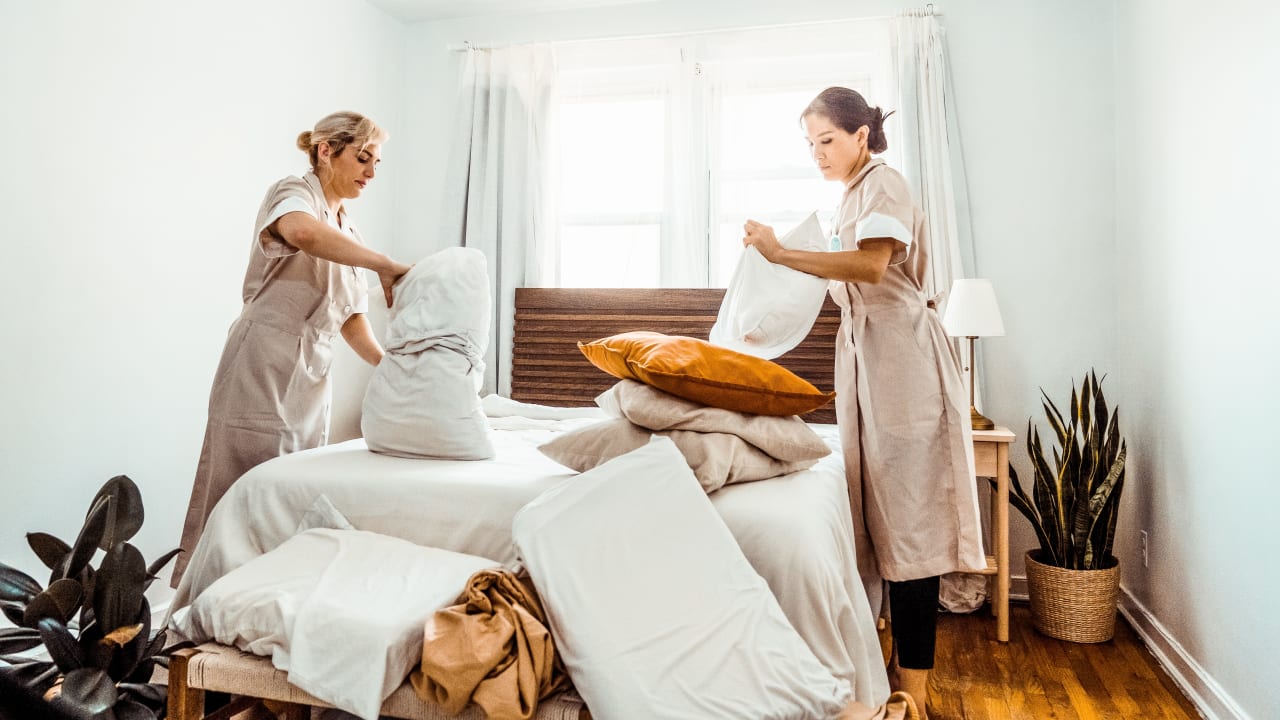 Two Gigpro housekeepers making a bed during a hotel shift. 