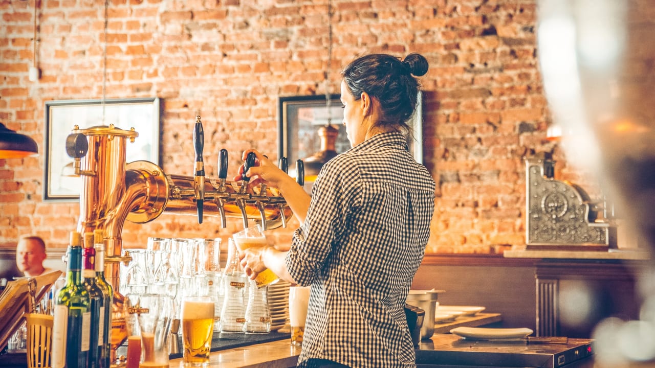 bartender at local restaurant serving draft beer.