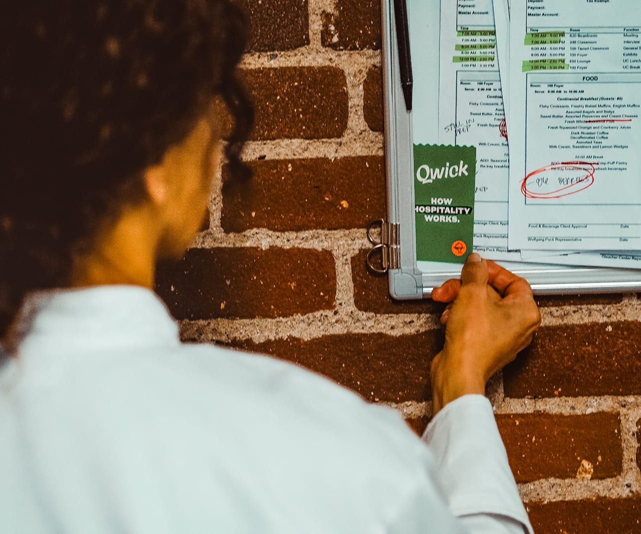 Worker reviewing a printed banquet event order pinned to a wall board