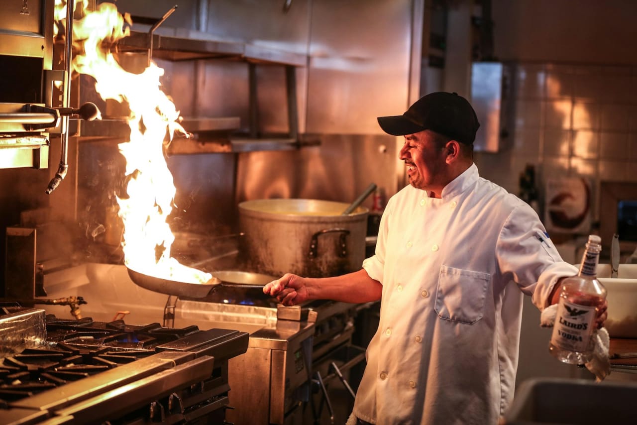 Chef cooking over an open flame on a restaurant range