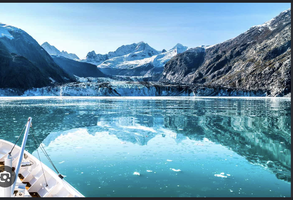 Snow-capped Alaskan mountains rising above calm blue water