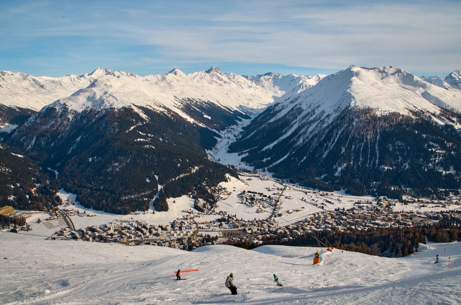 Skiers on the Davos slopes with snow-covered Alps beyond