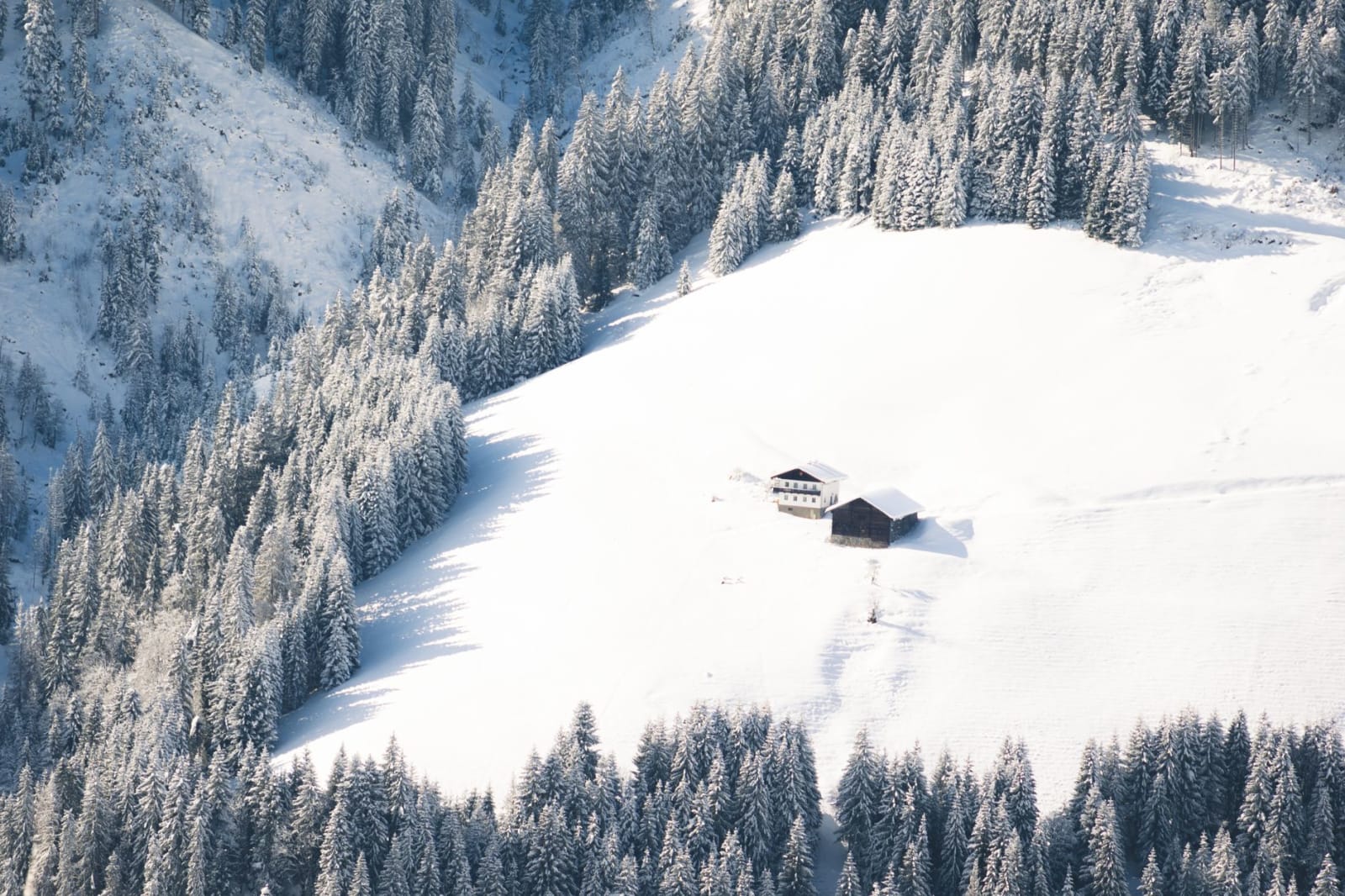 A stunning aerial view of a snow-covered landscape in Wagrain, Salzburg, featuring trees and a secluded village house.