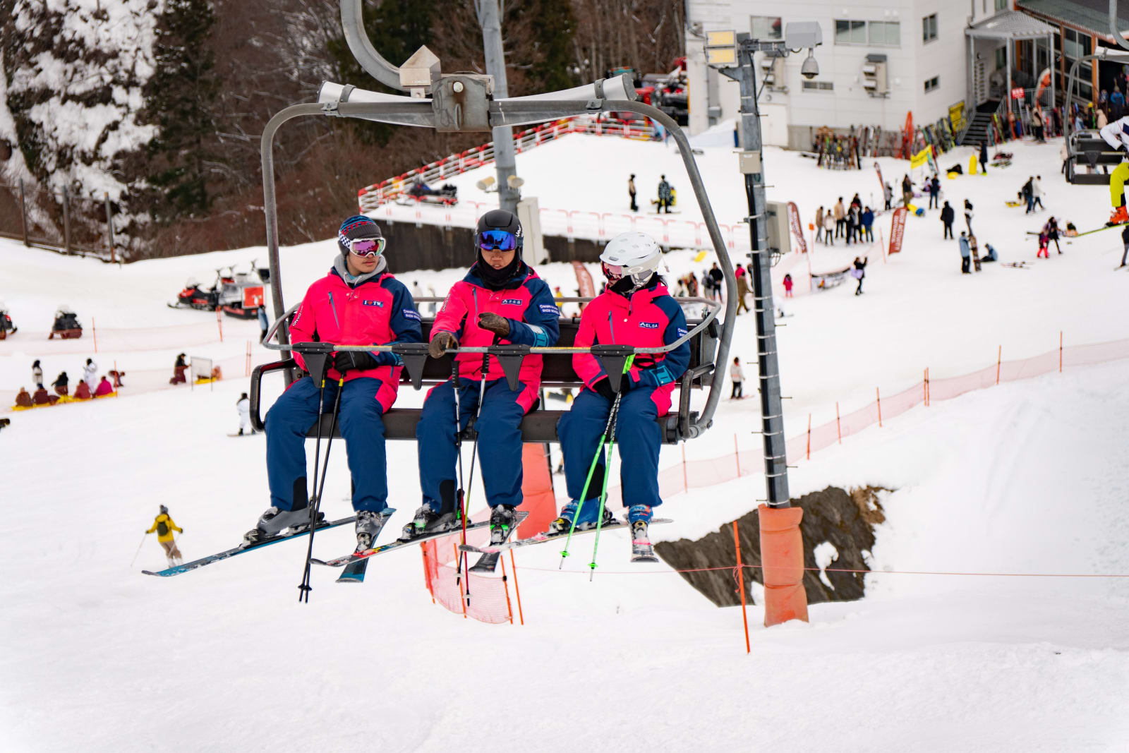 Three skiers in bright jackets on a chairlift in Yuzawa, Japan