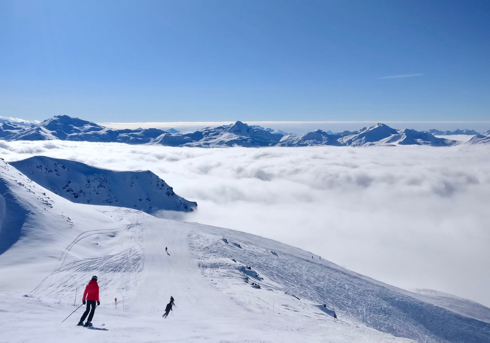 Skiers on a slope at Val Thorens above a sea of clouds
