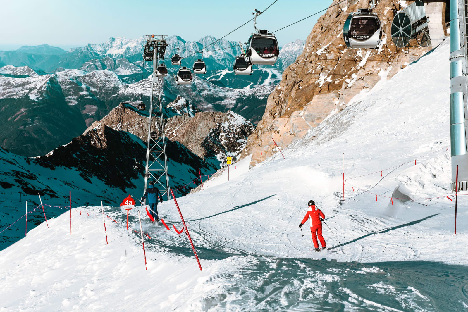 A skier descending a slope at Zell am See with cable cars and mountains behind