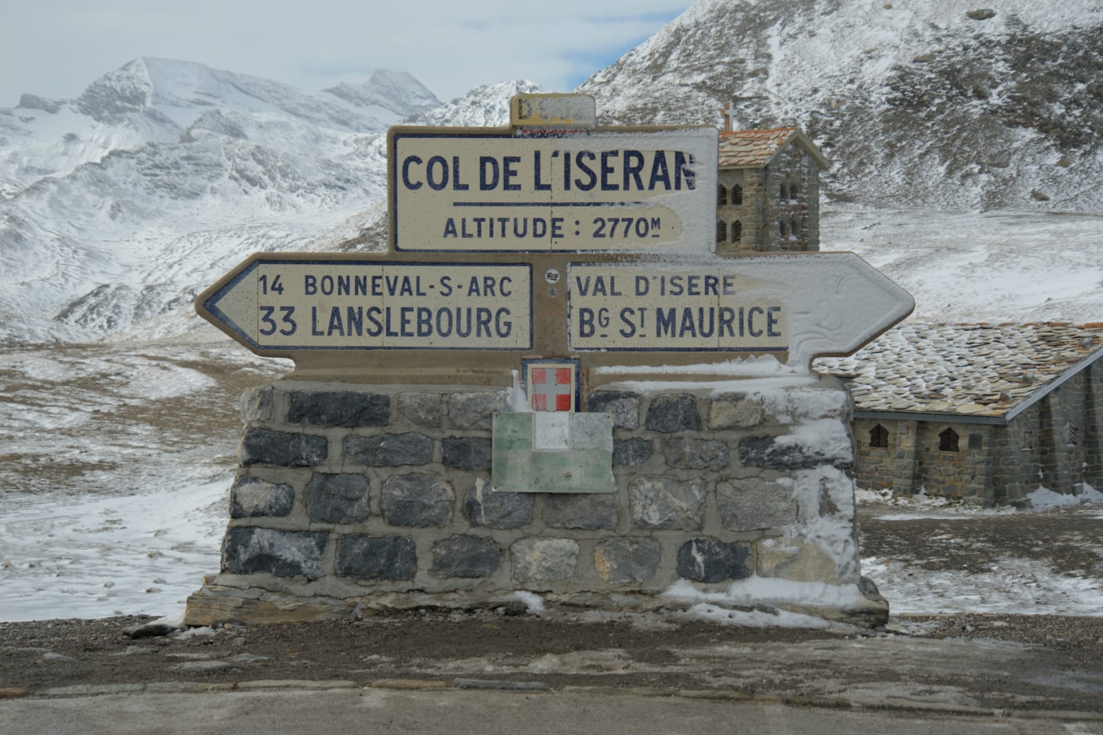 Snowy Col de l'Iseran signpost in Bonneval-sur-Arc, showcasing stunning alpine views.