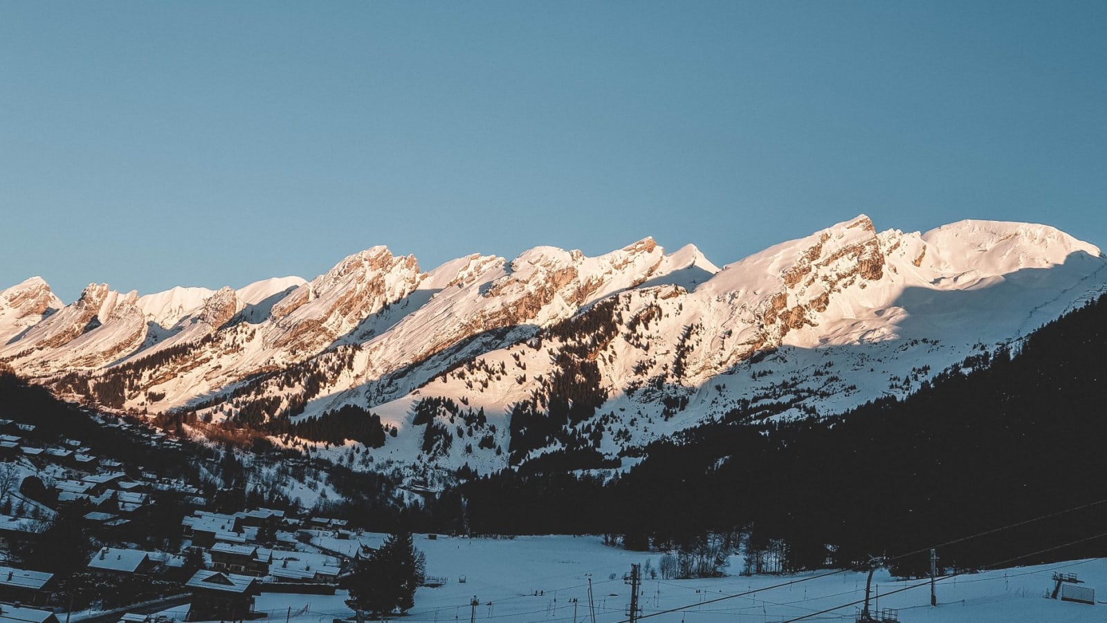 Breathtaking winter landscape of snowy mountains in La Clusaz, France during sunrise.