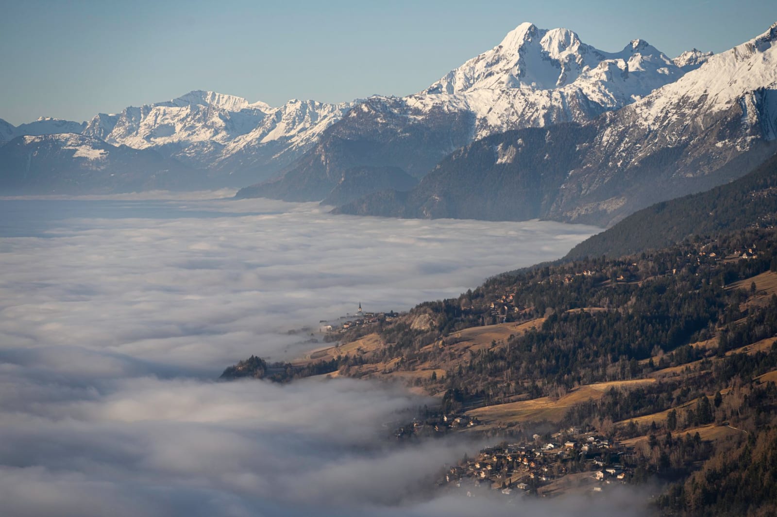 Breathtaking view of the Swiss Alps with a sea of clouds enveloping Crans-Montana at sunrise.