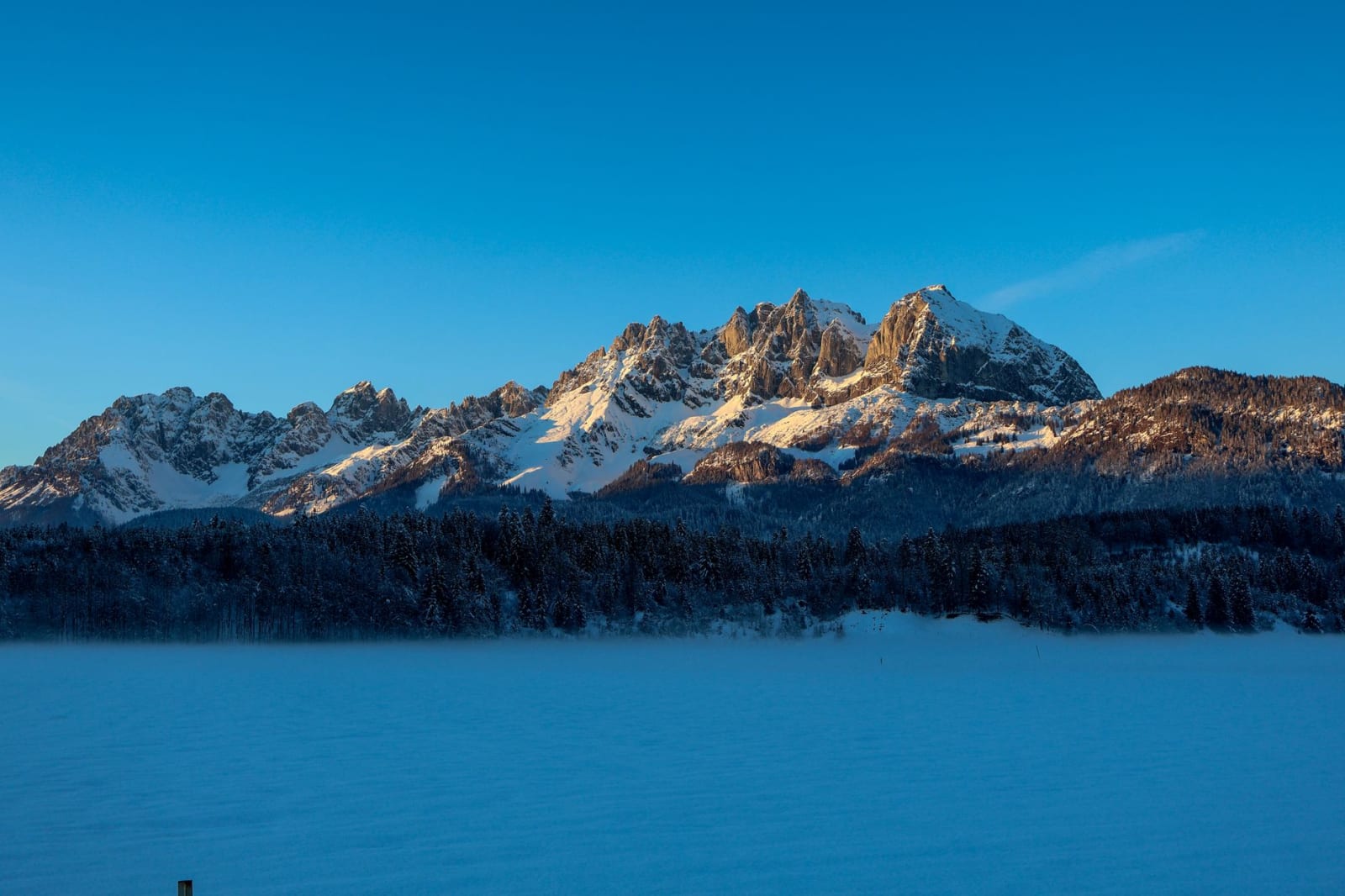 Stunning winter landscape of Wilder Kaiser mountains in Sankt Johann, Tirol with snowy peaks at sunrise.