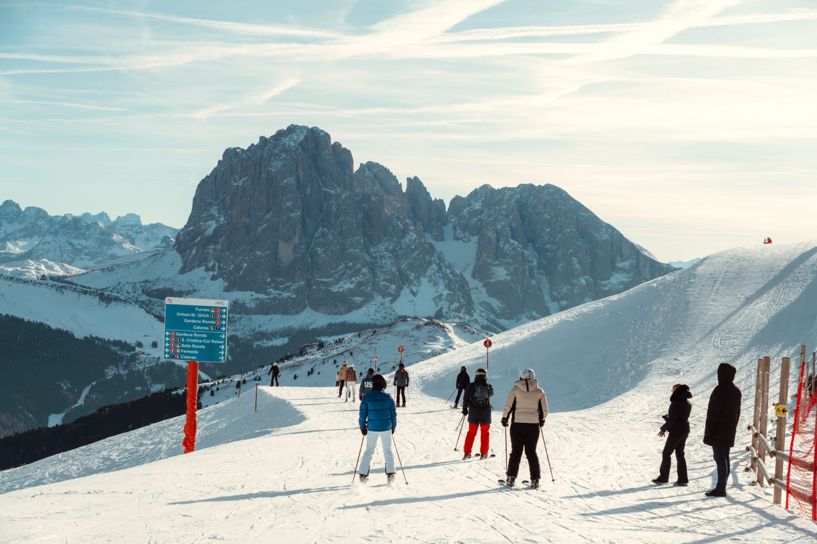 Skiers on a sunny slope with Dolomite peaks behind