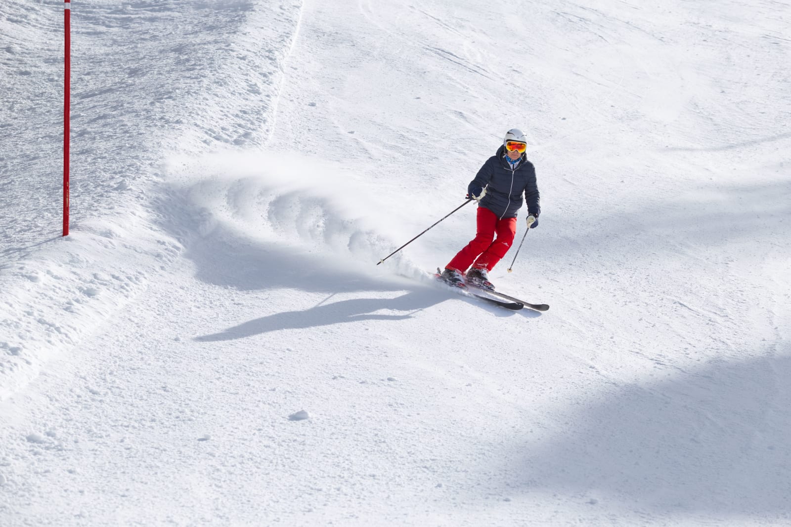 A skier carving a snowy slope on a sunny day