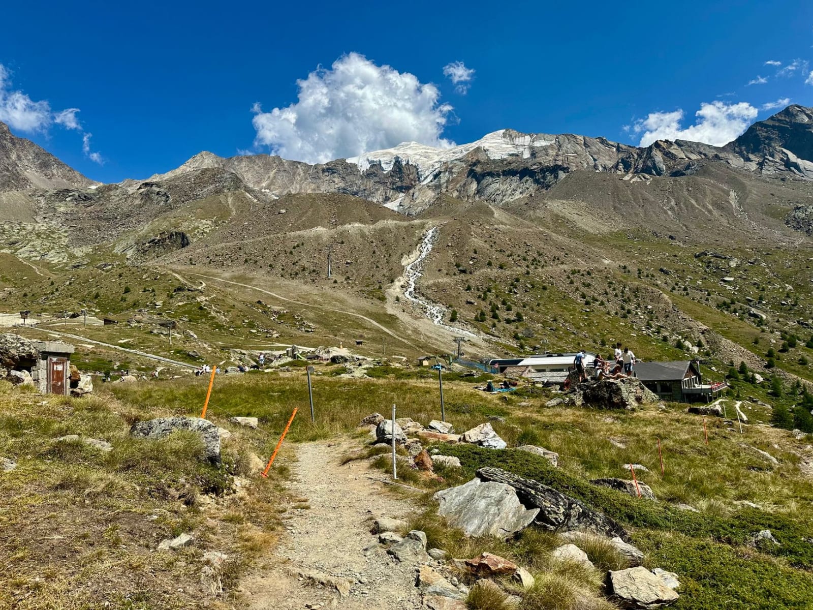 A breathtaking view of the Swiss Alps in Saas-Fee with hikers enjoying the summer landscape.