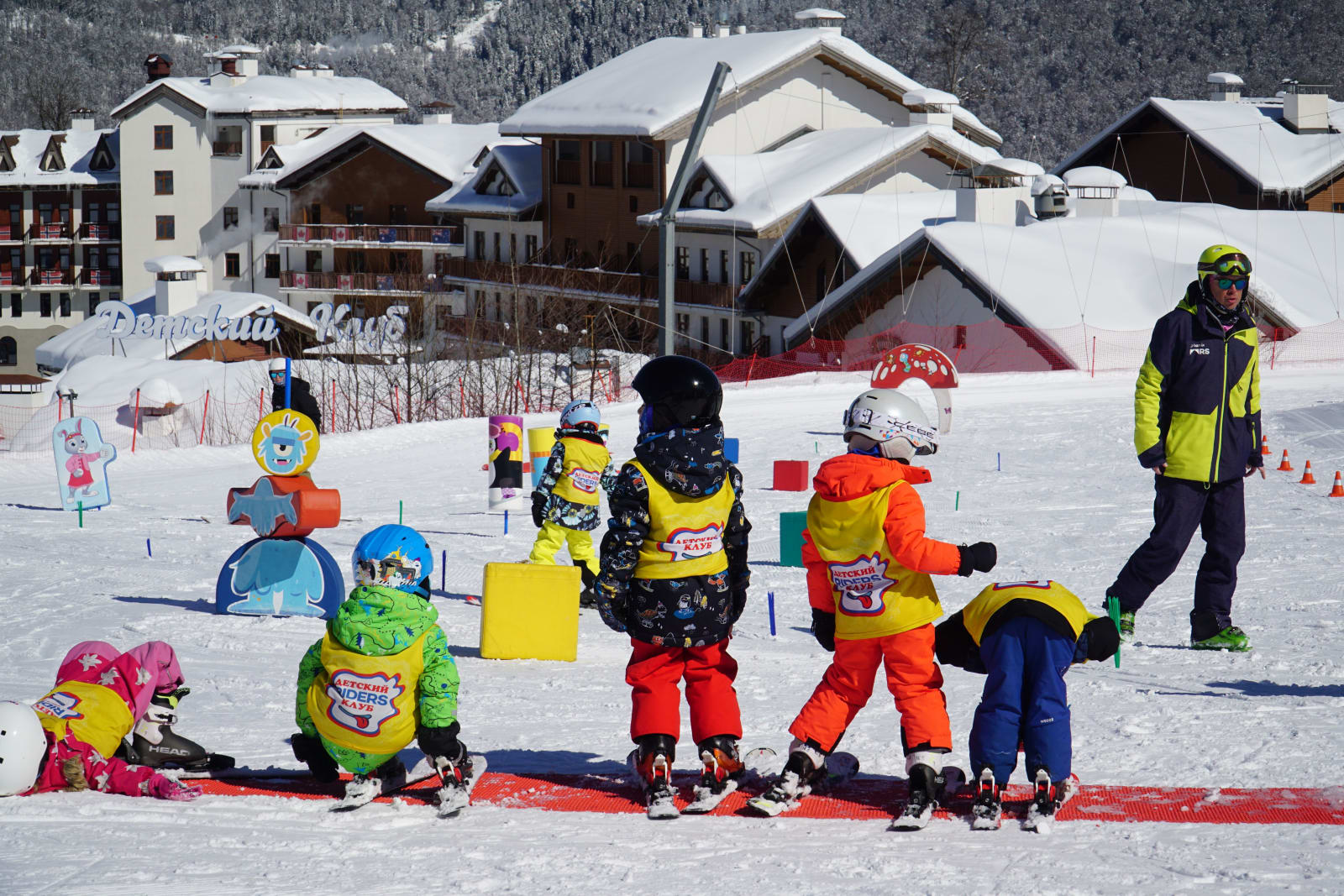 Children in colourful outfits in a ski lesson