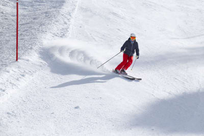 A skier carving a snowy slope on a sunny day