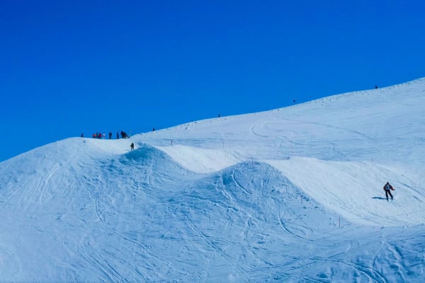 Capture of skiers navigating snowy slopes under a clear blue sky. Perfect winter adventure scene.
