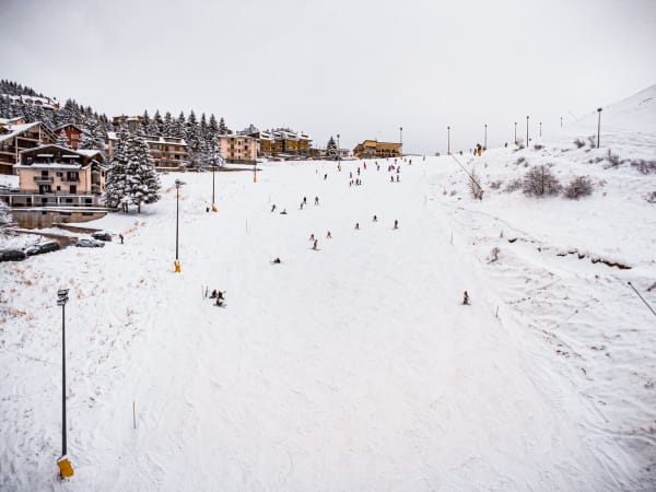 Diverse skiers enjoying a winter day on a snowy slope in a picturesque village.