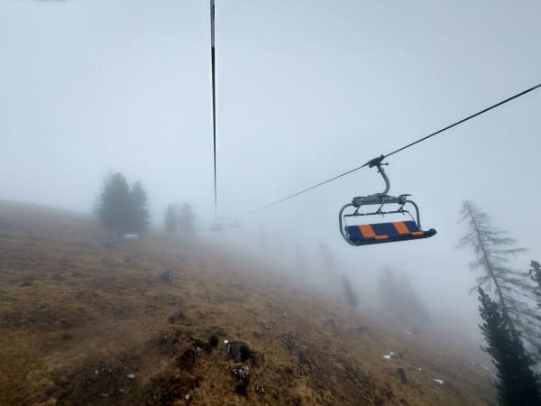 Illustrative photo: leaving february / Pexels A ski lift ascending a foggy mountain, surrounded by mist and sparse trees, creating a serene adventure scene.