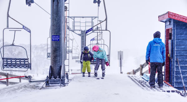 A family prepares to ride the ski lift at Selwyn Snow Resort on a snowy day.