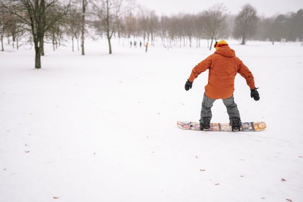 Illustrative photo: Yan Krukau / Pexels A snowboarder in a winter jacket glides on a snow-covered field surrounded by bare trees.