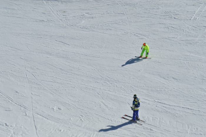 Aerial view of skiers enjoying the slopes during a sunny winter day, showcasing active winter sports.