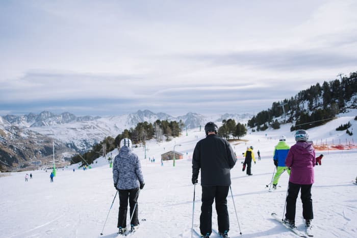 A group of skiers enjoying a winter day on a scenic ski slope with mountains in the backdrop.