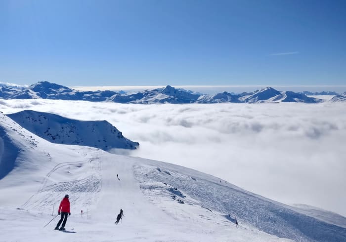 Skiers on a slope at Val Thorens above a sea of clouds