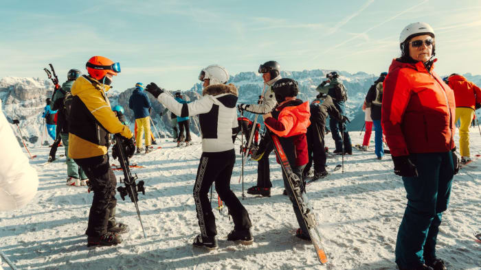Skiers gathered on a snowy mountain enjoying a sunny winter day with stunning mountain views.