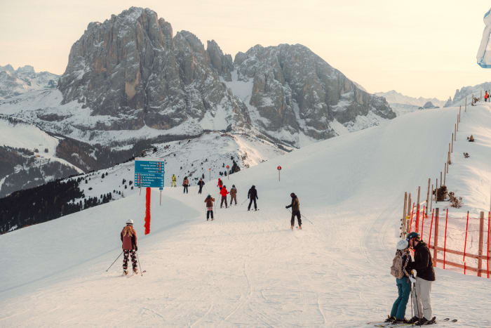 Skiers on a sunny slope below the Dolomites
