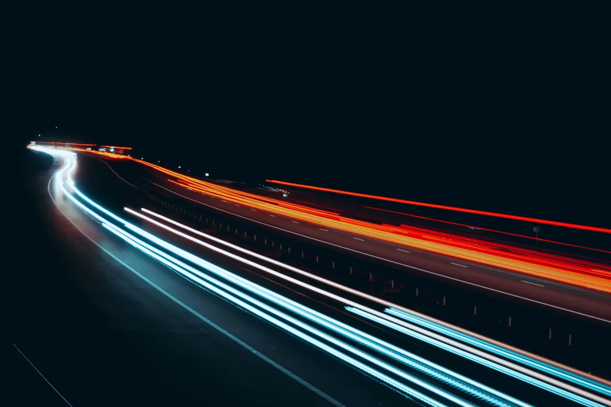 Traînées de lumière en pose longue sur une autoroute de nuit, symbolisant la vitesse de chargement et la performance web