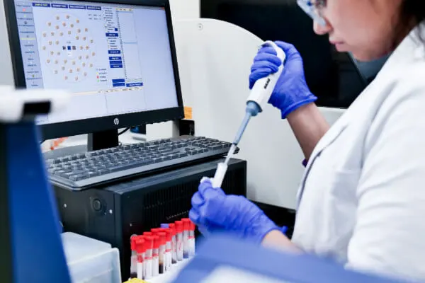 A veterinarian working with blood samples in a laboratory setting with test tubes and a computer