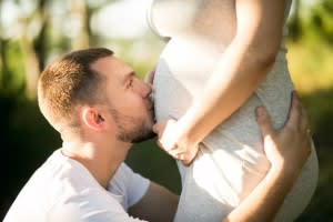 man kisses pregnant belly