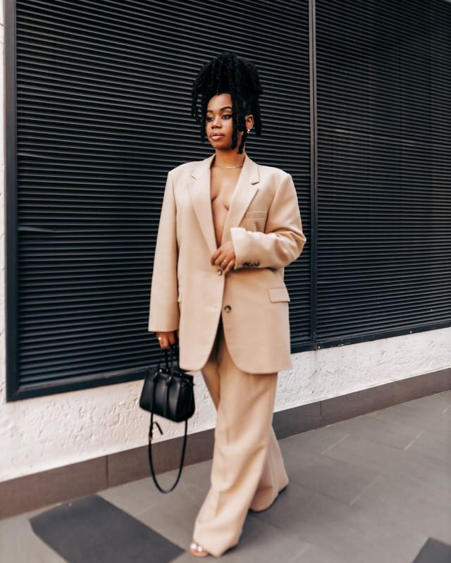 Sha Sha in a light brown blazer and pant set with a black bag featured as a fashionable African female artiste