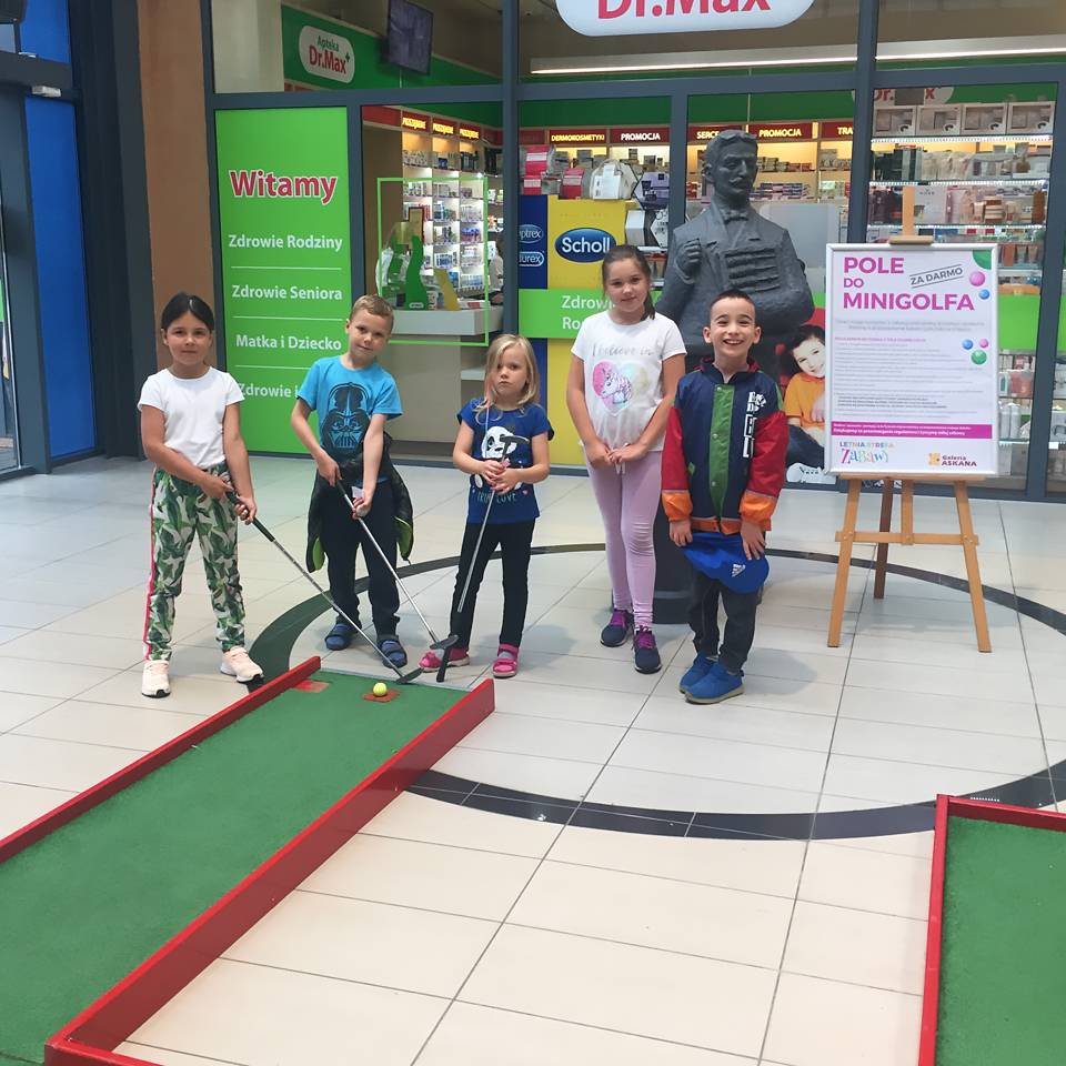 Pole do minigolfa w Galerii Handlowej Askana. Dzieci z kijami golfowymi.