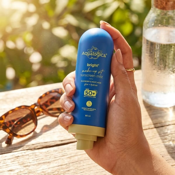 Aqualogica Bright+ Makeup-Set Sunscreen Mist SPF 50+ PA++++ with Blueberry & Kojic Acid held in hand, candid photo