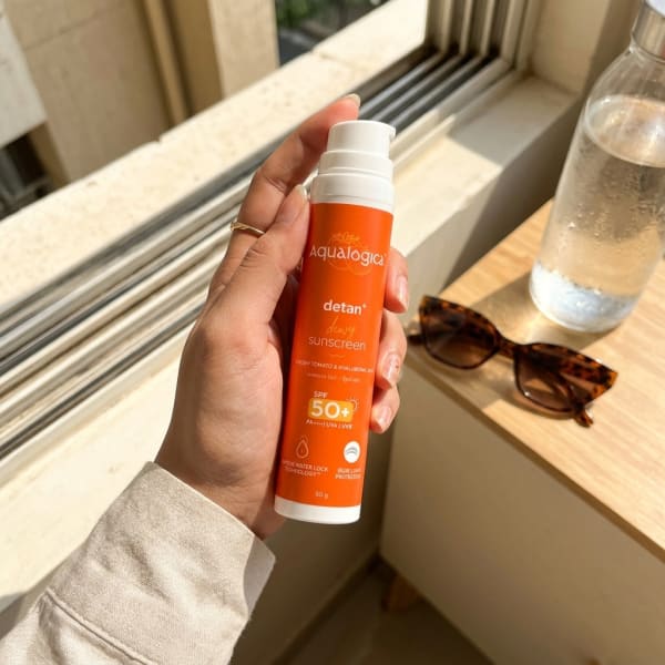 Aqualogica FREEBIE | Detan+ Dewy Sunscreen with SPF 50+ & PA++++ for UVA/B & Blue Light Protection & No White Cast - 50g held in hand, candid photo