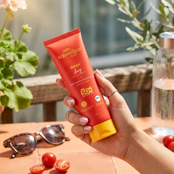 Aqualogica Detan+ Dewy Sunscreen, 125g held in hand, candid photo