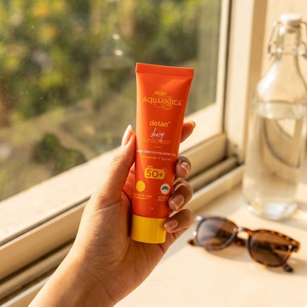 Aqualogica FREEBIE Detan+ Dewy Sunscreen 15g held in hand, candid photo