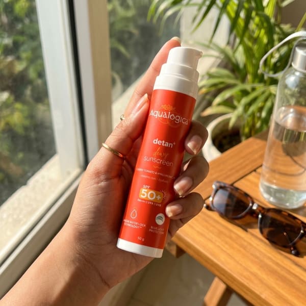 Aqualogica FREEBIE | Detan+ Dewy Sunscreen with SPF 50+ & PA++++ for UVA/B & Blue Light Protection & No White Cast - 50g held in hand, candid photo