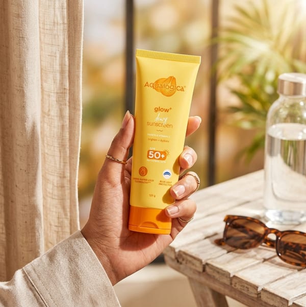 Aqualogica Glow+ Dewy Sunscreen 125g held in hand, candid photo